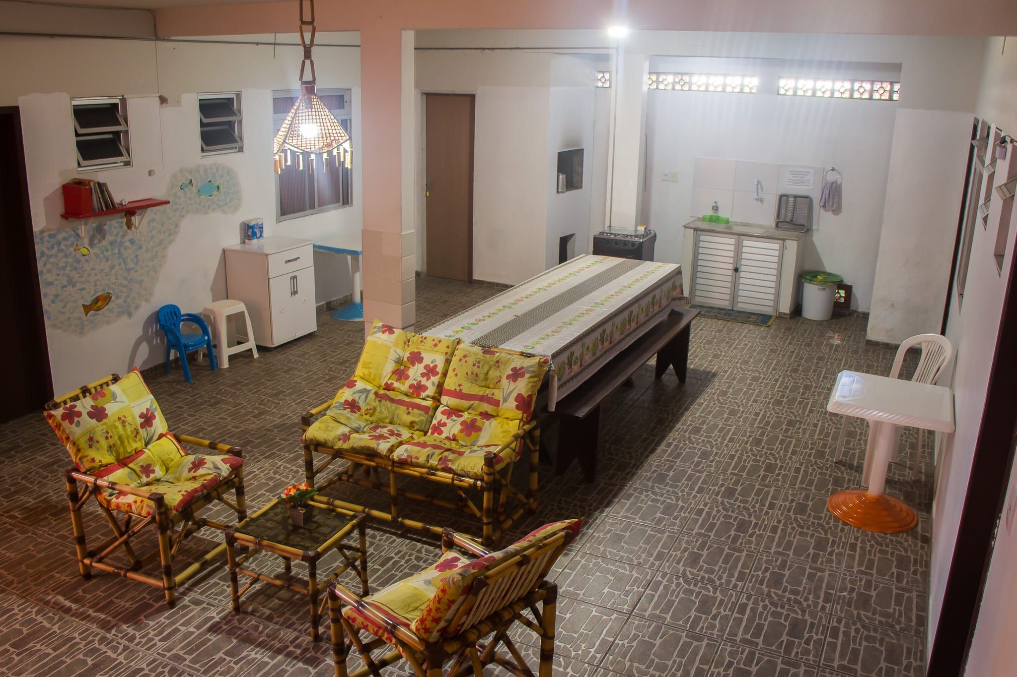 Cozinha compartilhada com mesa comprida e poltronas de bambu