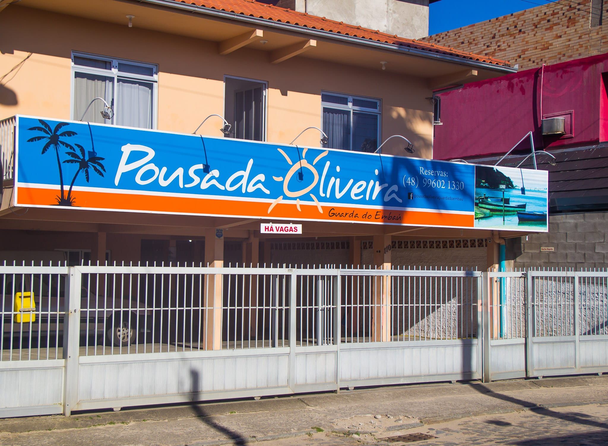 Fachada da Pousada Oliveira, com a placa azul e laranja
